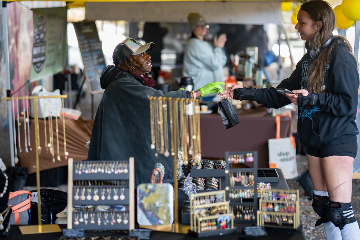 Christina Mondestin (left) owner of Beni Destiné jewelry, sells a necklace at her booth at the Atlanta Beltline Marketplace's annual Small Business Saturday event on Nov. 29, 2025. (Ben Hendren for the AJC)