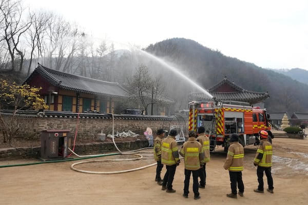 A firefighter vehicle sprays water in preparation for a possible approaching wildfire at a temple in Cheongsong, South Korea, Thursday, March 27, 2025. (AP Photo/Ahn Young-joon)