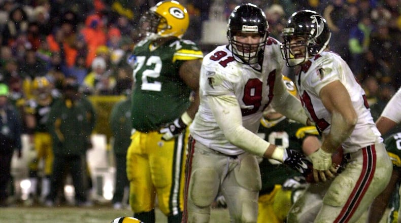 Packers quarterback Brett Favre sits dejected in the snow as Falcons defensive ends Brady Smith (center) and Patrick Kerney come up with his fumble celebrating during 4th quarter. (Curtis Compton/AJC)