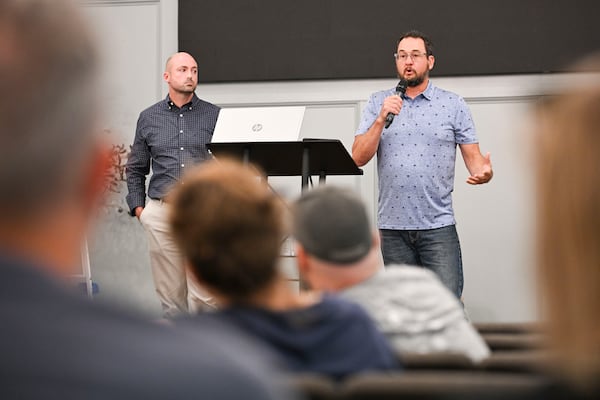 Howell Station Neighborhood Association Board Member Chad Murray (left) and President Chris Alasa address residents gathered at the M28 Church in Howell Station in April to discuss the impact a QTS data center campus is having on the neighborhood. (Daniel Varnado/for the AJC)