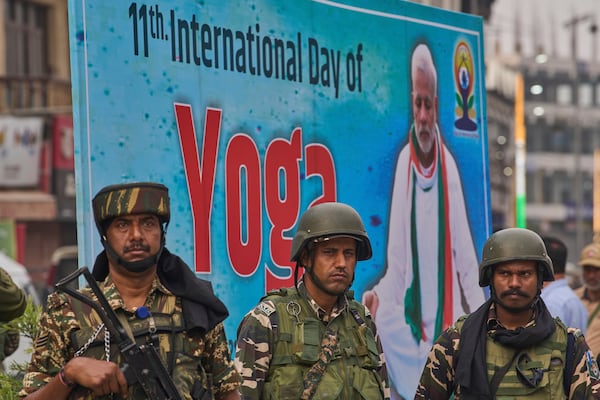 Indian paramilitary soldiers stand guard as people perform yoga on International Day of Yoga at the city centre in Srinagar, Indian controlled Kashmir, Saturday, June 21, 2025. (AP Photo/Dar Yasin)