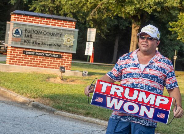 Dion Cini holds his Donld Trump sign outside of the Fulton County Jail on Wednesday in Atlanta. (Michael Blackshire/Michael.blackshire@ajc.com)