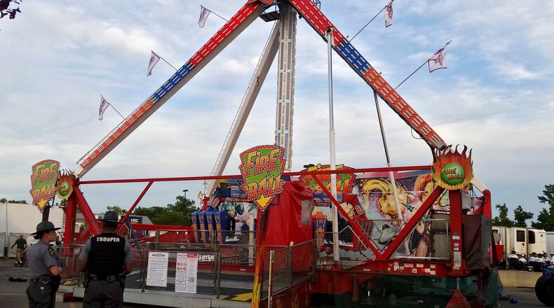 Authorities stand near the Fire Ball amusement ride after the ride malfunctioned injuring several at the Ohio State Fair, Wednesday, July 26, 2017, in Columbus, Ohio. Some of the victims were thrown from the ride when it malfunctioned Wednesday night, said Columbus Fire Battalion Chief Steve Martin. (Jim Woods/The Columbus Dispatch via AP)
