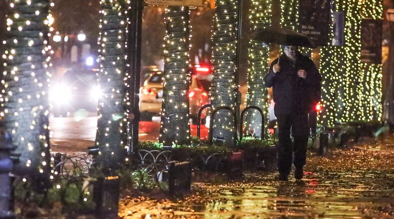 Mike Huerta makes his way past the Christmas lights strung along the trees on Peachtree Street near 8th street early Thursday. JOHN SPINK / JSPINK@AJC.COM