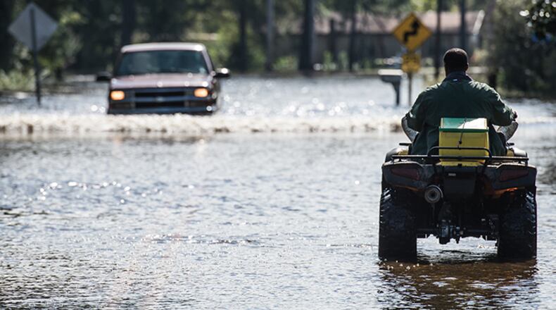 A man navigates a flooded street on a four wheeler in the Browns Ferry community Oct. 11, 2015 near Georgetown, S.C.