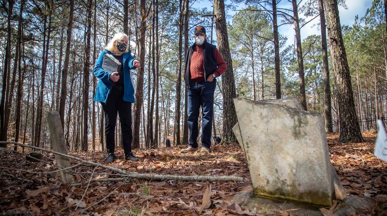 Johns Creek's Historical Society president Joan Compton (L) and Johns Creek's Historical Society Board Member Kirk Canaday look over a headstone at the Macedonia Cemetery in 2021. Johns Creek is might form a nonprofit that would provide guidance in the restoration and preservation of a cemetery where former enslaved people and their relatives are buried. STEVE SCHAEFER FOR THE ATLANTA JOURNAL-CONSTITUTION