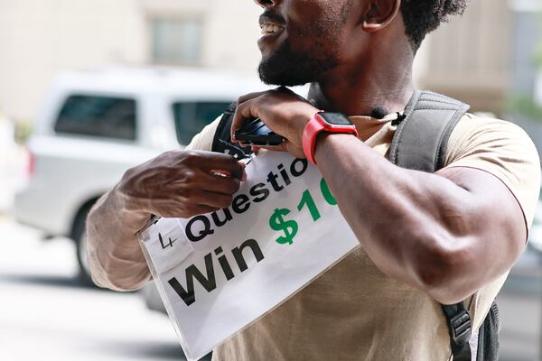 TikTok star Leon Ondieki pins a sign to his backpack before starting his trivia game on Friday, July 22, 2022. (Natrice Miller/natrice.miller@ajc.com)