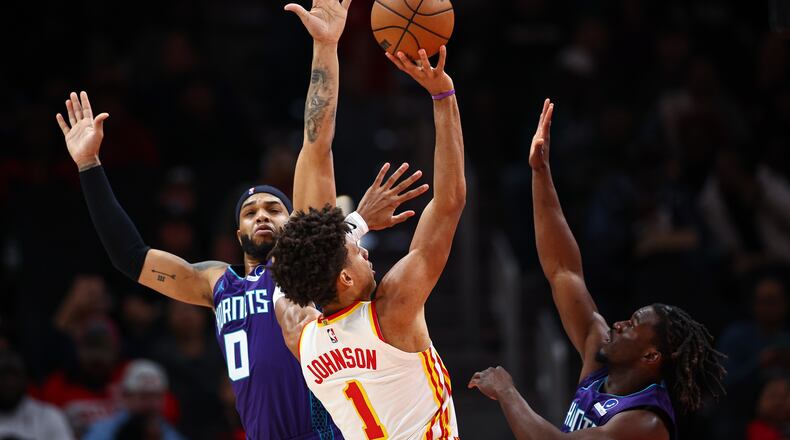 Atlanta Hawks forward Jalen Johnson (1) shoots against Charlotte Hornets forward Miles Bridges (0) and guard Sion James, right, during the first half of an NBA basketball game, Sunday, Nov. 23, 2025, in Atlanta. (AP Photo/Colin Hubbard)