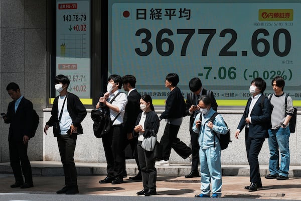 People stand in front of an electronic stock board showing Japan's Nikkei index at a securities firm Thursday, May 8, 2025, in Tokyo. (AP Photo/Eugene Hoshiko)