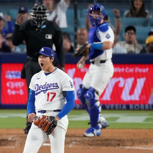 Los Angeles Dodgers two-way player Shohei Ohtani, center, reacts after striking out San Francisco Giants' Rafael Devers, left, as catcher Will Smith gets ready to throw the ball back during the sixth inning of a baseball game Wednesday, May 13, 2026, in Los Angeles. (AP Photo/Mark J. Terrill)