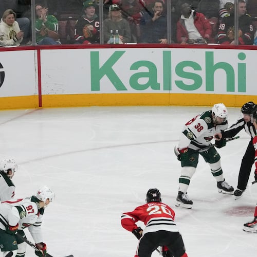 A face-off during the third period of an NHL hockey game between the Chicago Blackhawks and the Minnesota Wild with the Kalshi sign in the background Tuesday, March, 17, 2026, in Chicago. (AP Photo/David Banks)