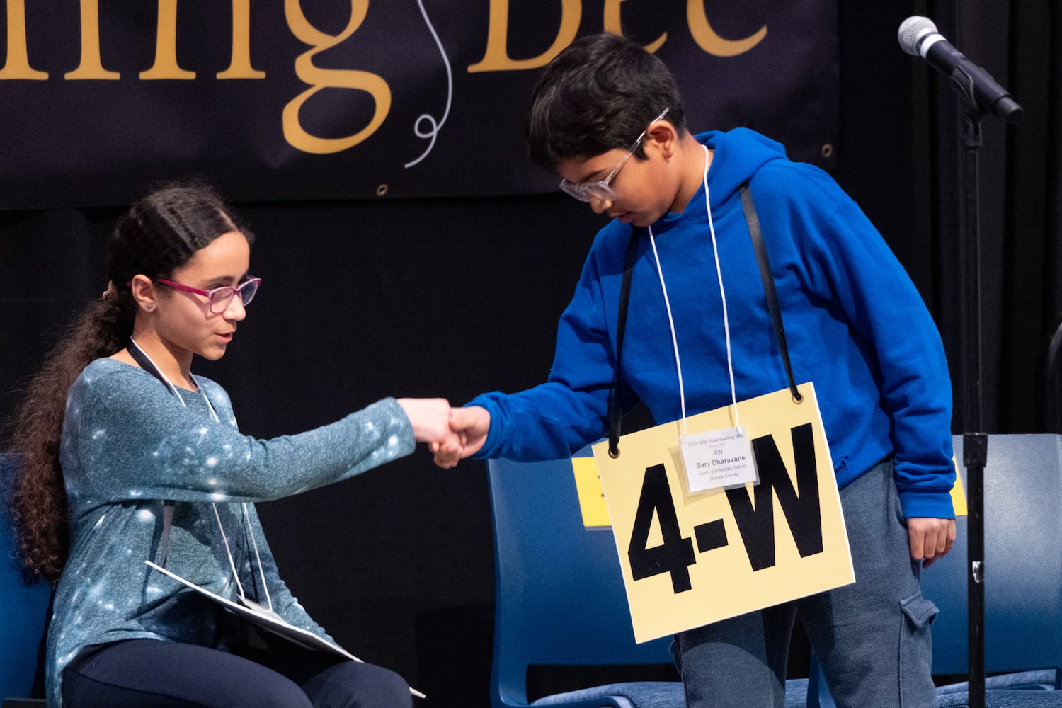 Sarv Dharavane shakes hands with Sara Daoud after beating her to win the GAE State Spelling Bee Championship at Georgia State University in Atlanta on Friday, March 21, 2025.   Ben Gray for the Atlanta Journal-Constitution