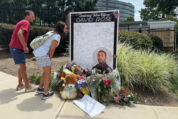 People leave flowers at a makeshift memorial in honor of David Rose, the officer who was killed in the shooting at the CDC headquarters.