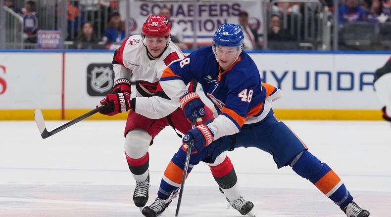 New York Islanders' Matthew Schaefer (48) drives past Carolina Hurricanes' Eric Robinson (50) during the second period of an NHL hockey game Tuesday, April 14, 2026, in Elmont, N.Y. (AP Photo/Frank Franklin II)