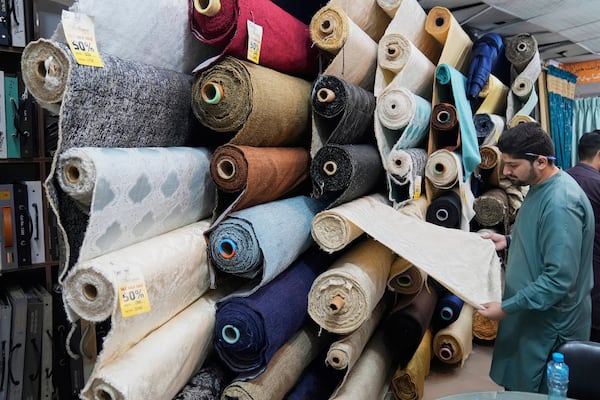A vendor displays linen sofa fabric in a house linens store at a market in Lahore, Pakistan, Thursday, April 3, 2025. (AP Photo/K.M. Chaudary)