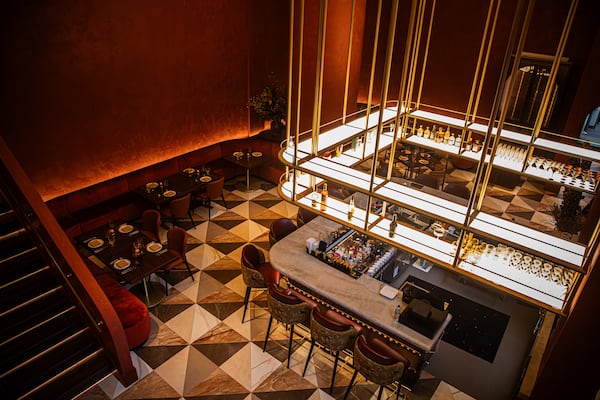 A look from a mezzanine level down into the dining room of a modern restaurant dominated by a square, U-shaped bar.