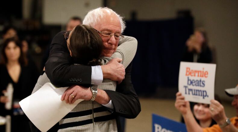 Democratic presidential candidate Sen. Bernie Sanders, I-Vt., center, hugs Rep. Alexandria Ocasio-Cortez, D-N.Y., after Sanders walked up to the podium to speak during a campaign event Saturday, Jan. 25, 2020, in Marshalltown, Iowa. (AP Photo/Marcio Jose Sanchez)