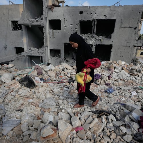 A resident carries belongings as she walks through the rubble of her home destroyed in an Israeli airstrike a day earlier in the southern village of Maarakeh, Lebanon, Wednesday, May 27, 2026. (AP Photo/Mohammed Zaatari)