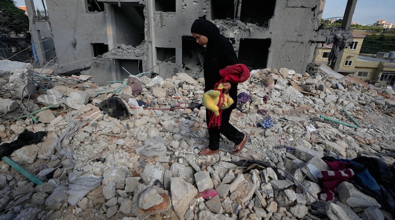 A resident carries belongings as she walks through the rubble of her home destroyed in an Israeli airstrike a day earlier in the southern village of Maarakeh, Lebanon, Wednesday, May 27, 2026. (AP Photo/Mohammed Zaatari)