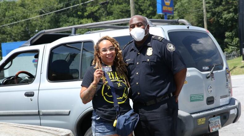 A police officer poses with a local woman as the Atlanta Police Department distributes 1,000 Kroger gift cards of $50 each donated by media mogul Tyler Perry.