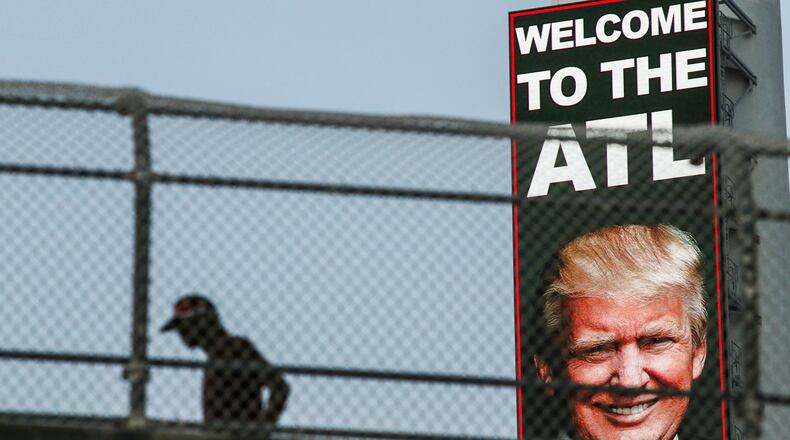 June 15, 2016 Atlanta: A pedestrian makes his way across the Decatur Street bridge nearby the welcome sign and image of presumed Republican presidential nominee Donald Trump that loomed over the Atlanta downtown connector visible to southbound motorists. JOHN SPINK /JSPINK@AJC.COM