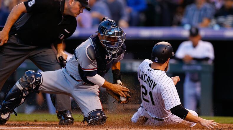 Jonathan Lucroy of the Colorado Rockies slides safely under the tag of catcher Kurt Suzuki of the Atlanta Braves as home plate as umpire Dan Bellino looks on during the second inning at Coors Field Wednesday. Lucroy was called out on the play but the call was reversed after video replay. (Photo by Justin Edmonds/Getty Images)
