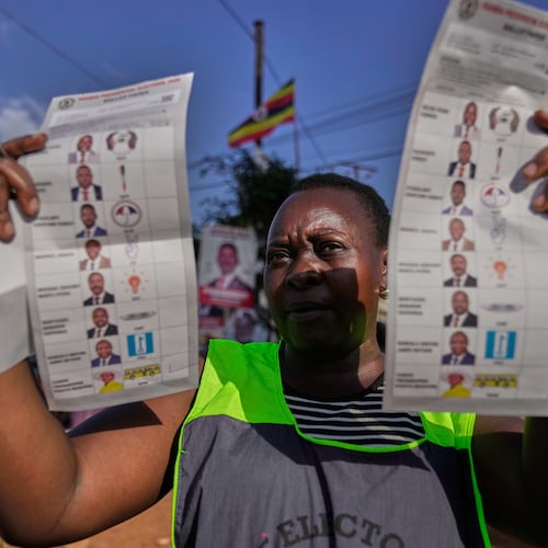 An election official holds up unmarked ballots during the vote count after polls closed for the presidential election, at a polling center in Kampala, Uganda, Thursday, Jan. 15, 2026. (AP Photo/Brian Inganga)
