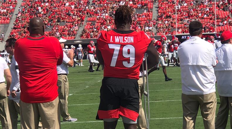 Starting right tackle Isaiah Wilson (79), watching Saturday's warmups with UGA administrator Jonas Jennings (L), remains sidelined with a left ankle injury. (Photo by Chip Towers/ctowers@ajc.com)