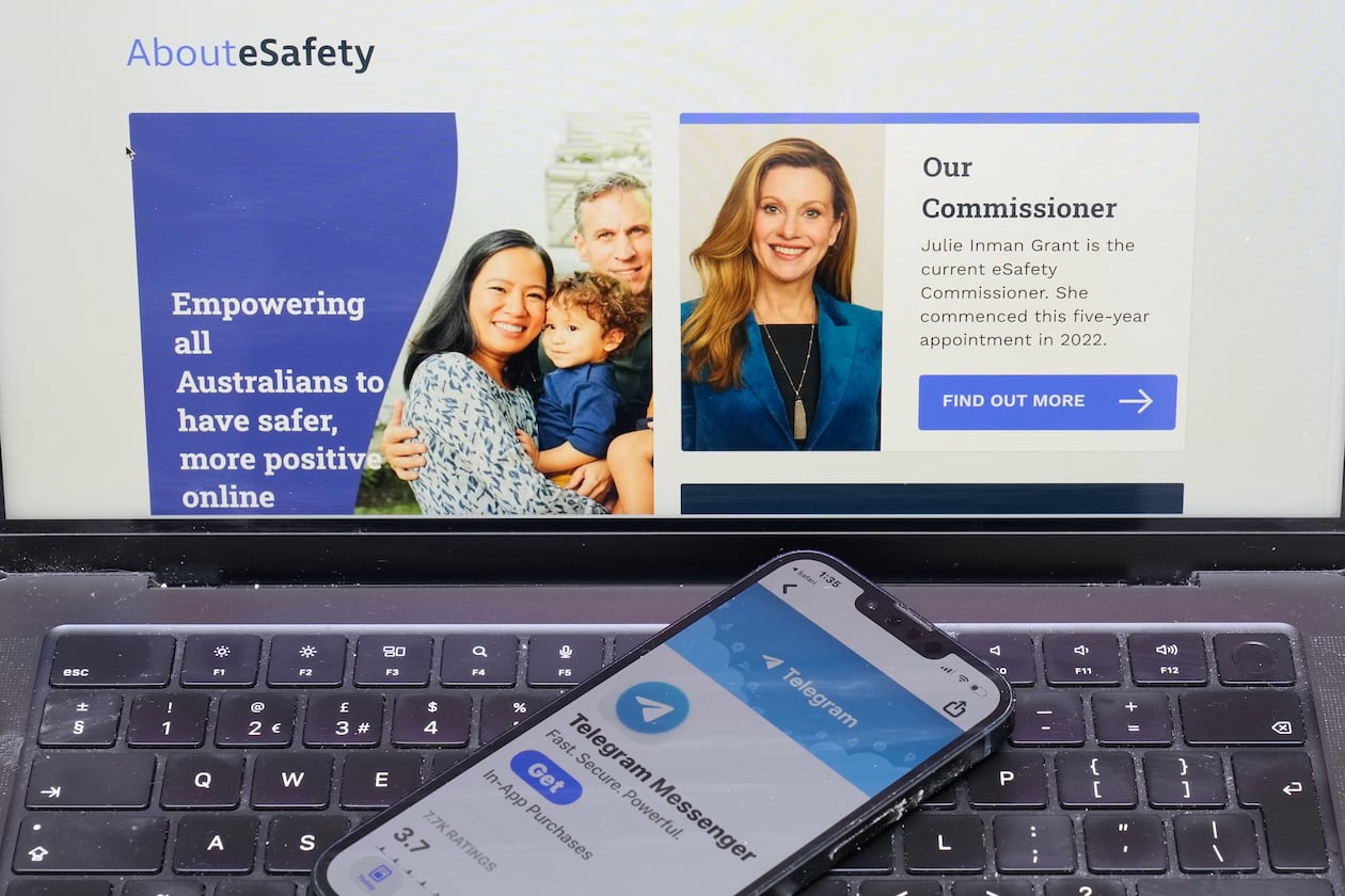 A phone rests on a computer showing the Australian eSafety web page in Sydney, Thursday, July 30, 2026. (AP Photo/Rick Rycroft)