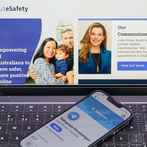 A phone rests on a computer showing the Australian eSafety web page in Sydney, Thursday, July 30, 2026. (AP Photo/Rick Rycroft)