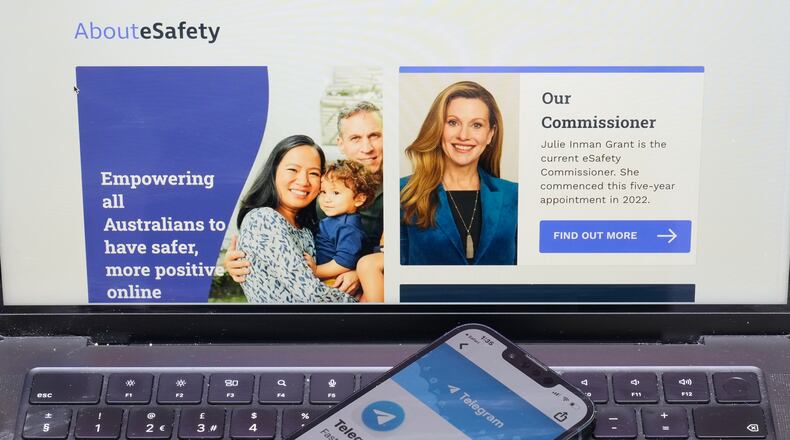 A phone rests on a computer showing the Australian eSafety web page in Sydney, Thursday, July 30, 2026. (AP Photo/Rick Rycroft)