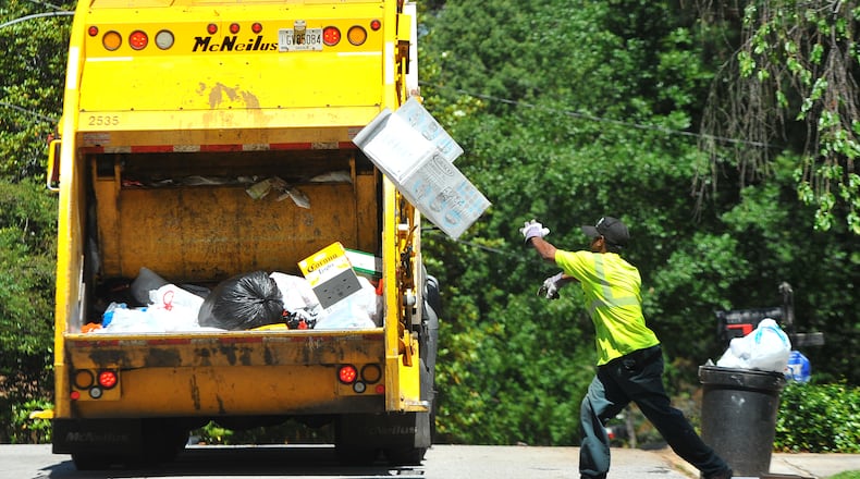 DeKalb County sanitation worker Larry Wyatt tosses trash into the truck  May 10, 2012.  BRANT SANDERLIN / AJC.COM