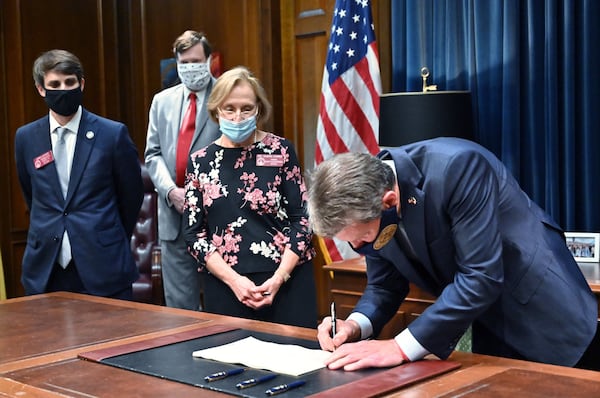 Gov. Brian Kemp in 2020 signs House Bill 987, the senior care reform bill, into law as, from left, Rep. John LaHood (R-Valdosta), Joe Hood of the Georgia Department of Community Health, and Rep. Sharon Cooper (R-Marietta) watch. (Hyosub Shin / Hyosub.Shin@ajc.com)