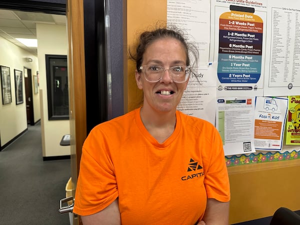 Theresa Gibbs stands near a poster showing typical food expiration dates as she awaits food supplies at the Samaritan Center food pantry on Tuesday, July 1, 2025, in Jefferson City, Mo. (AP Photo/David A. Lieb)