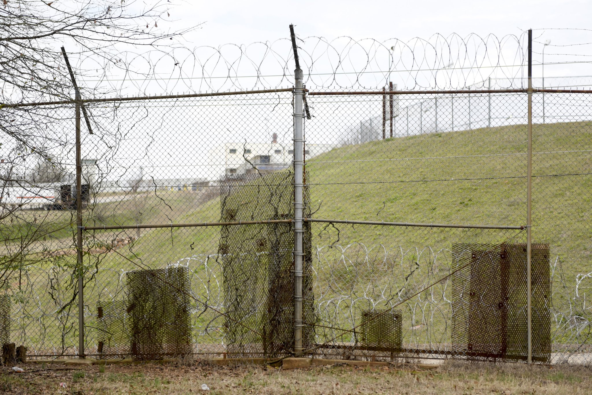 Patches of metal are bolted to the fence along the United States Penitentiary in Atlanta to cover holes used by the minimum-security inmates to smuggle contraband into the camps. (DAVID BARNES / SPECIAL)
