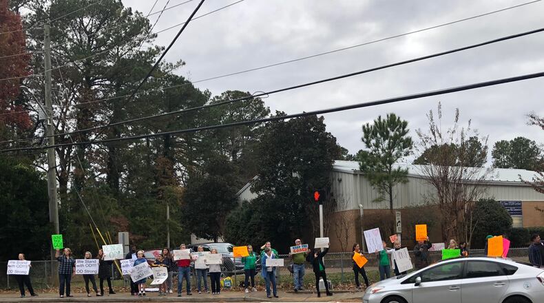 Several dozen protesters march along Henderson Mill Road in front of Henderson Mill Elementary School in late November to support longtime physical education teacher James O’Donnell, who was suspended by DeKalb County School District officials for how he punished one of his students. MARLON A. WALKER / MARLON.WALKER@AJC.COM