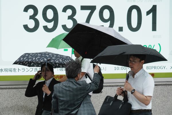 People walk in front of an electronic stock board showing Japan's Nikkei index at a securities firm Monday, July 14, 2025, in Tokyo. (AP Photo/Eugene Hoshiko)
