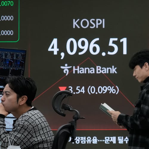 A currency trader watches monitors near a screen showing the Korea Composite Stock Price Index (KOSPI) at the foreign exchange dealing room of the Hana Bank headquarters in Seoul, South Korea, Monday, Dec. 8, 2025. (AP Photo/Ahn Young-joon)