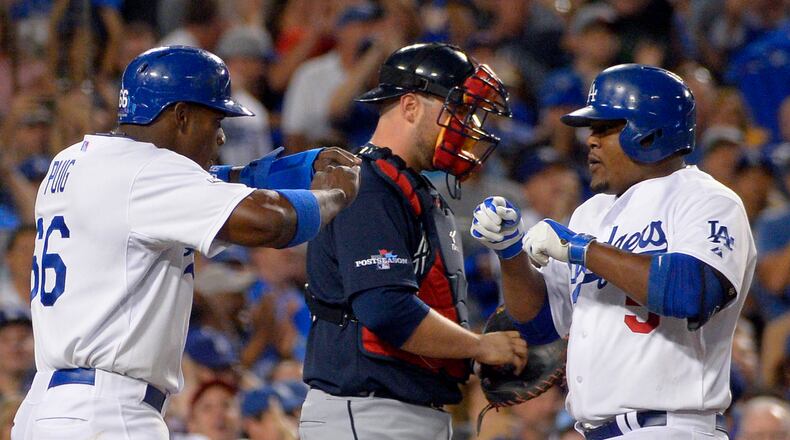 Los Angeles Dodgers' Juan Uribe, right, greets Dodgers' Yasiel Puig, left, at the plate next to Atlanta Braves catcher Brian McCann, center, after Uribe hit a two-run home run to score Puig in the fourth inning in Game 3 of the National League division baseball series Sunday, Oct. 6, 2013, in Los Angeles. (AP Photo/Mark J. Terrill)