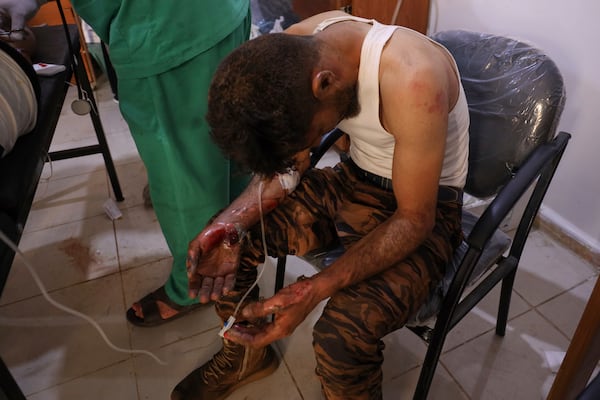 A Syrian government soldier who was injured in Sweida city during clashes between the government troops and Druze militias, waits for treatment at a clinic in Busra al-Harir village, southern Syria, Tuesday, July 15, 2025. (AP Photo/Omar Albam)