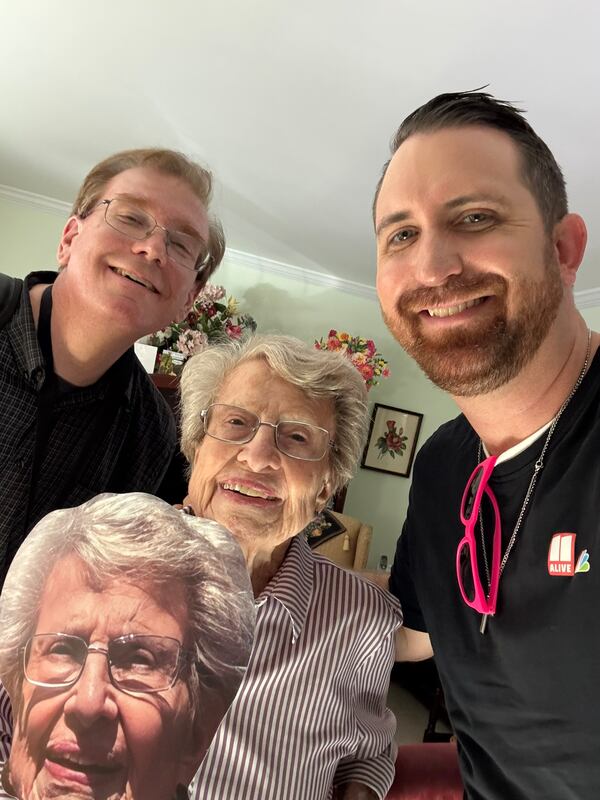 Barbara Haig (center, holding a fan with her face on it) poses with AJC columnist Doug Turnbull (right) and 11Alive photojournalist Stephen Boissy. (Doug Turnbull for the AJC)