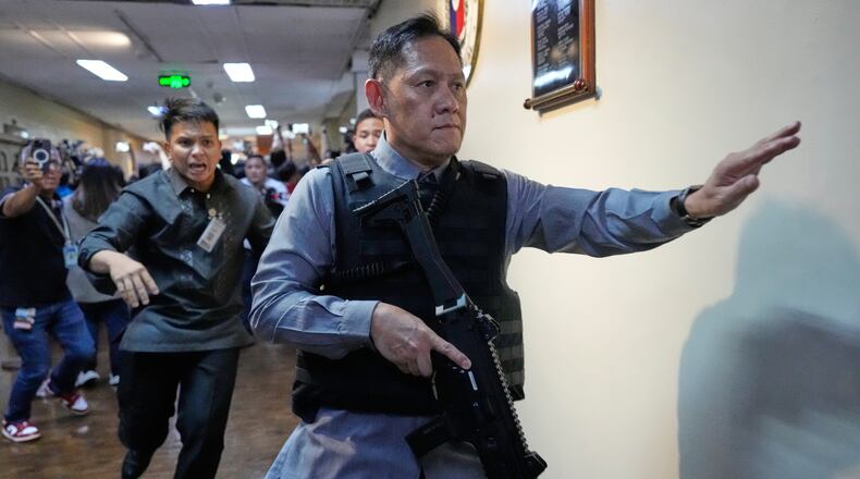 Senate security run after gunfire was heard along a hallway at the Philippine Senate in Pasay, Philippines, Wednesday, May 13, 2026. (AP Photo/Aaron Favila)