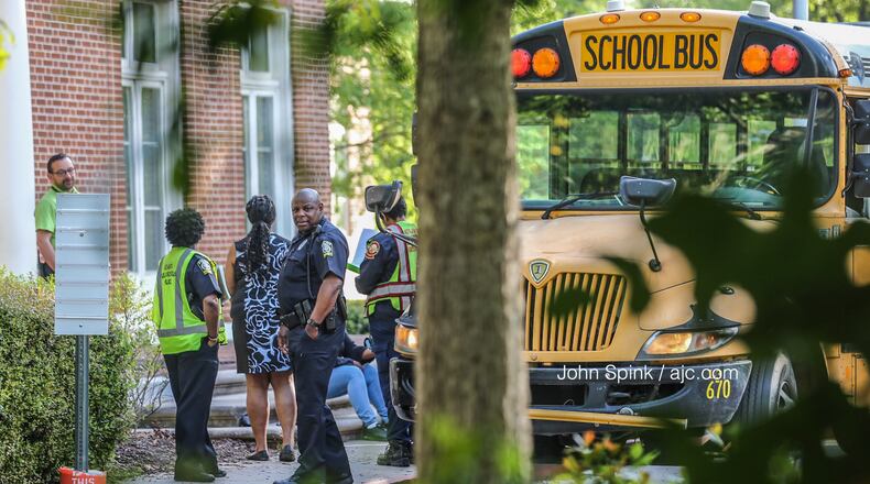 Atlanta fire paramedics speak with school officials outside Springdale Elementary after a school bus was grazed by a truck twice as it was turning into the school’s bus lane. No one was reported injured.