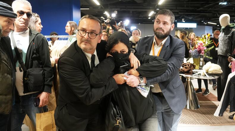 A protester is being evacuated from the BHV department store as fast fashion Shein opens its first physical store, Wednesday, Nov. 5, 2025 in Paris. (AP Photo/Thibault Camus)