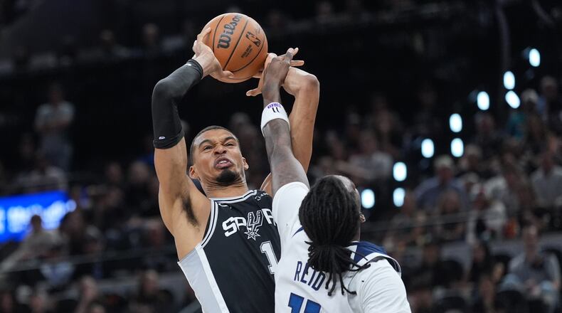 San Antonio Spurs forward Victor Wembanyama (1) grabs a rebound over Minnesota Timberwolves center Naz Reid (11) during the first half of Game 5 of an NBA basketball second-round playoffs series in Minneapolis, Tuesday, May 12, 2026. (AP Photo/Eric Gay)