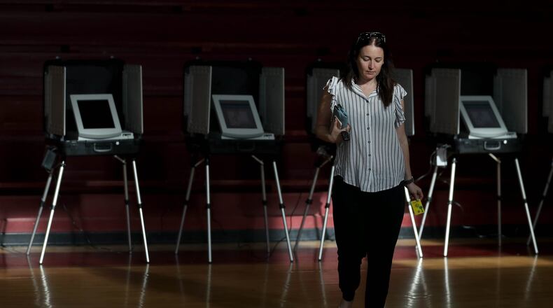 Sunlight streams through the windows of the gym as Dawn Churi walks away from the voting booths after voting Tuesday during the Georgia runoff election at Henry W. Grady High School in Atlanta. (JASON GETZ/SPECIAL TO THE AJC)