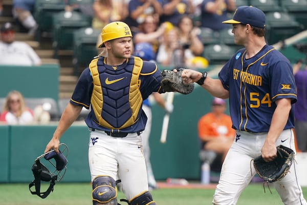 FILE - West Virginia catcher Logan Sauve, left, fist bumps Griffin Kirn (54) during an NCAA regional college baseball game against Kentucky, May 30, 2025, in Clemson, S.C. (AP Photo/Sean Rayford, File)