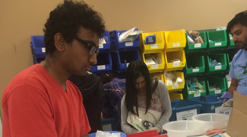 Amal Bhatnagar, 17, a senior at Fulton County's Northview High School, sorts and packages adhesive bandages, Band Aids and other basic health kits that would help patients with basic care as part of a volunteer effort with Medshare, a nonprofit that sends medical supplies to mission hospitals across the world. In the background are First Aid For All members Nicole Mistry (middle) and Soumil Nariani (right). Bhatnagar started a nonprofit to provide health supplies to impoverished communities. PHOTO CONTRIBUTED.