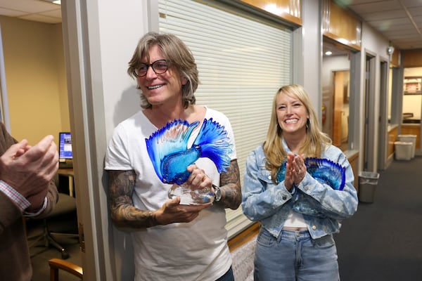 Kevin Avery and Taylor Scott receive glass fish from colleagues following the final broadcast of the Kevin & Taylor Show at the Fish 104.7 at their studio, Friday, Jan. 31, 2025, in Atlanta. (Jason Getz/AJC)