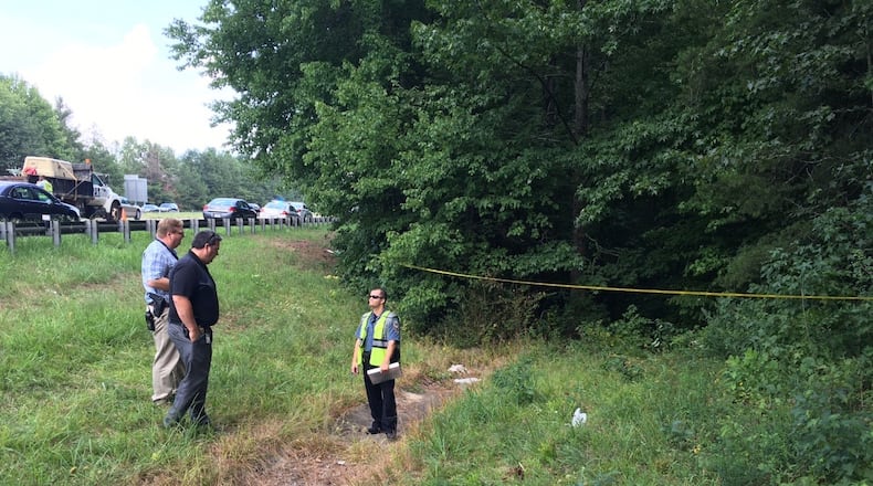 Police investigate the scene where a human skull and bones were found in a suitcase in a wooded area next to an interstate in Gwinnett County (Credit: Gwinnett County Police Department).